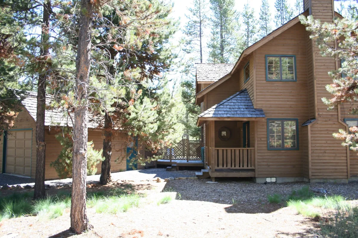 This exterior image showcases the home’s wooden façade, a spacious porch, and the surrounding Sunriver forest. The driveway hints at convenient access, while the tall trees emphasize the property’s immersive natural setting—perfect for launching family adventures right from the doorstep.