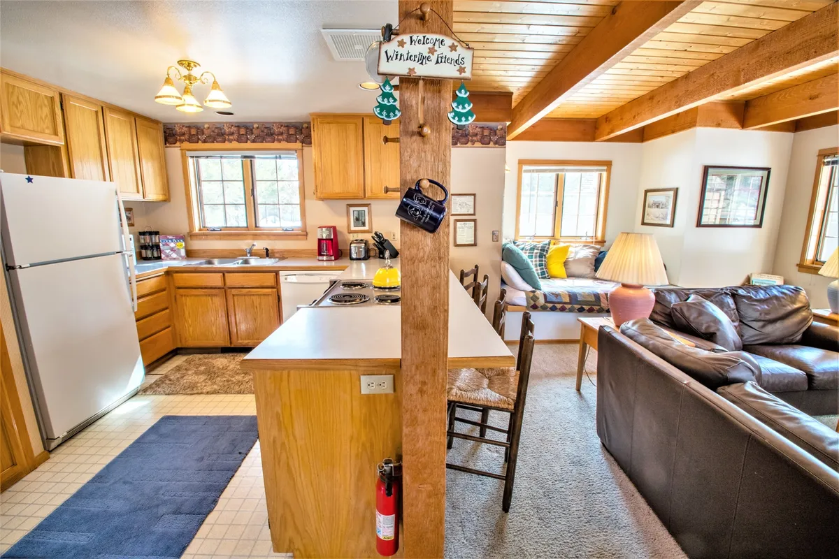 This cozy interior scene captures a kitchen island adjacent to a comfortable sofa and a dining area. The setup invites group activities, like cooking together and relaxing after meals, while the dining area in the background hints at the pleasure of sharing home-cooked feasts.