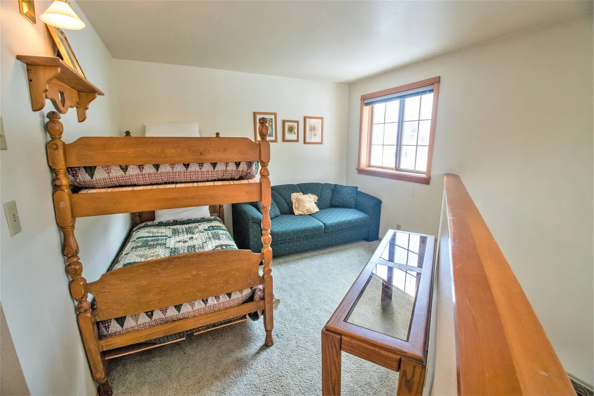An inviting interior shot of a cozy room featuring a bunk bed, sofa, and coffee table, designed as a fun space for kids to relax after a day outdoors. The setting is playful and comfortable, ideal for unwinding and family bonding.
